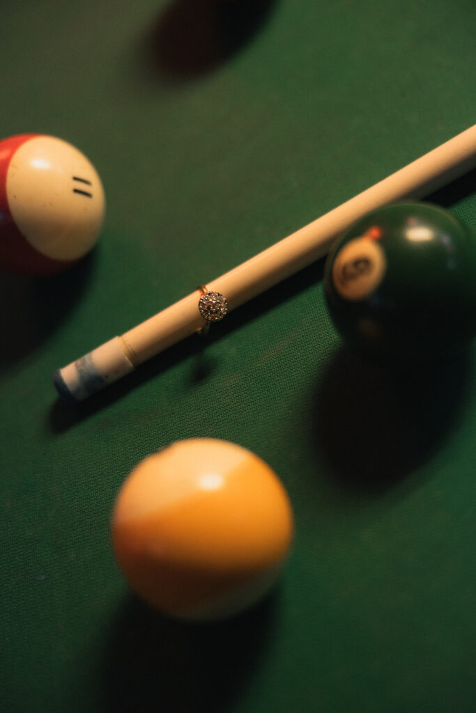 Close-up of cue stick tip touching orange striped ball on green felt
