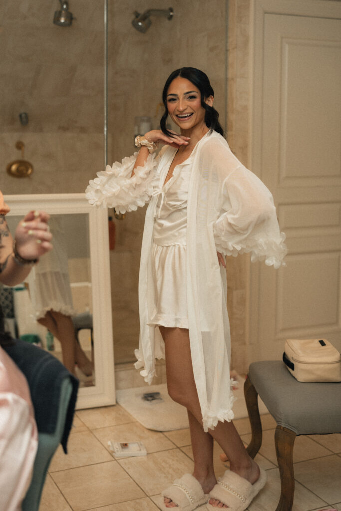 Bride laughing in silk robe before getting into wedding dress