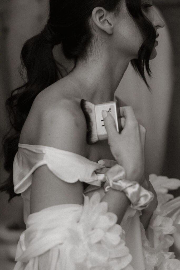 Bride getting ready in silk robe with wedding day makeup application