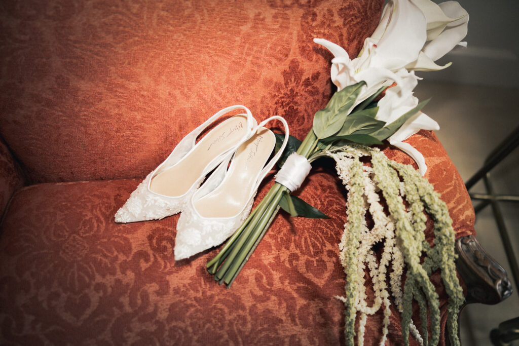 Bridal shoes and bouquet resting on vintage armchair