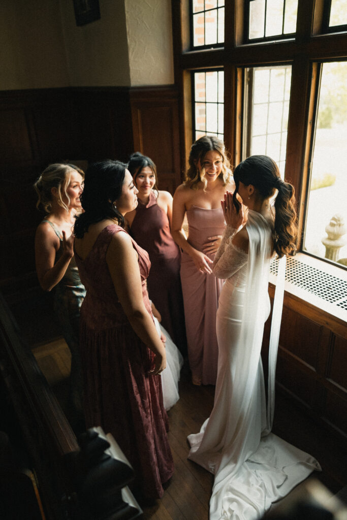Bridesmaids surrounding bride by window before ceremony, Triangle NC wedding