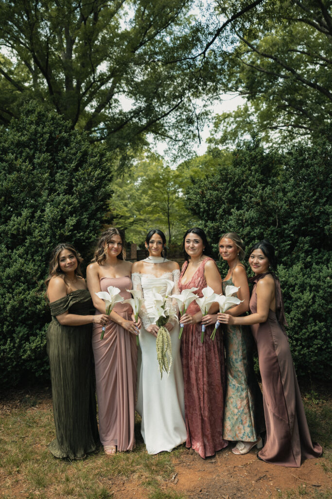 Bride and bridesmaids in mismatched mauve and olive dresses outdoors