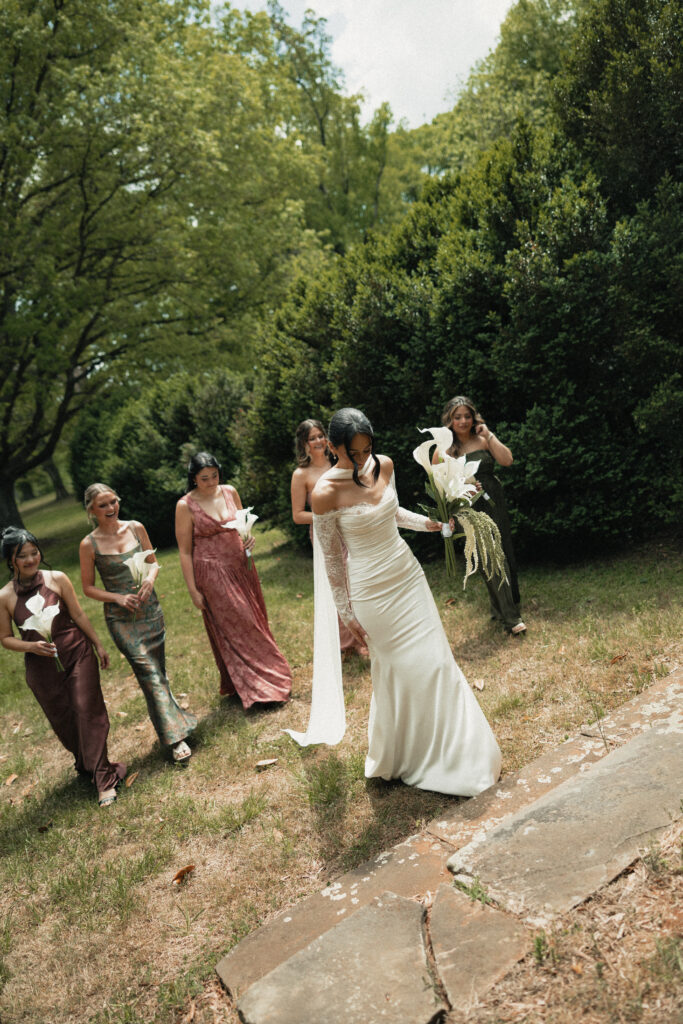 Bride and bridesmaids walking through garden with calla lily bouquets