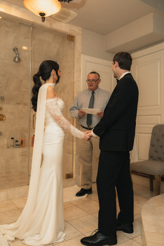Bride and groom holding hands during private ceremony, officiant reading vows