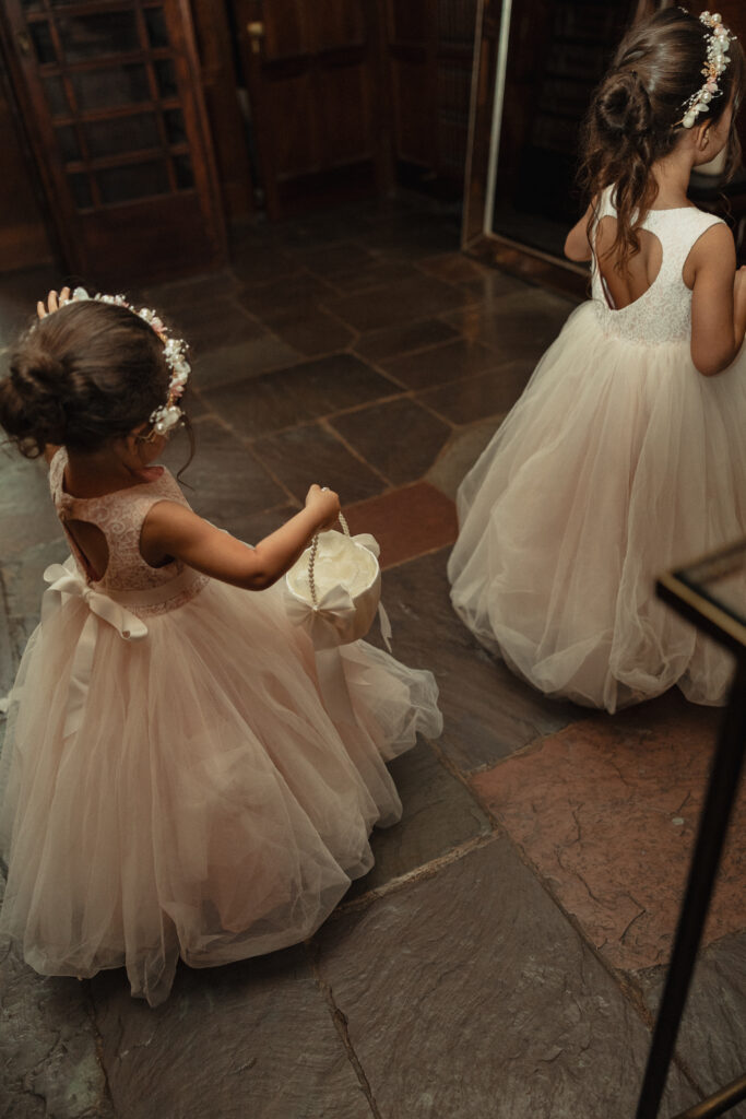 Flower girls in tulle dresses walking into ceremony space
