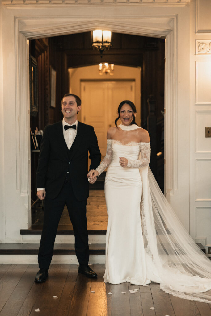 Bride and groom laughing while walking through venue doorway