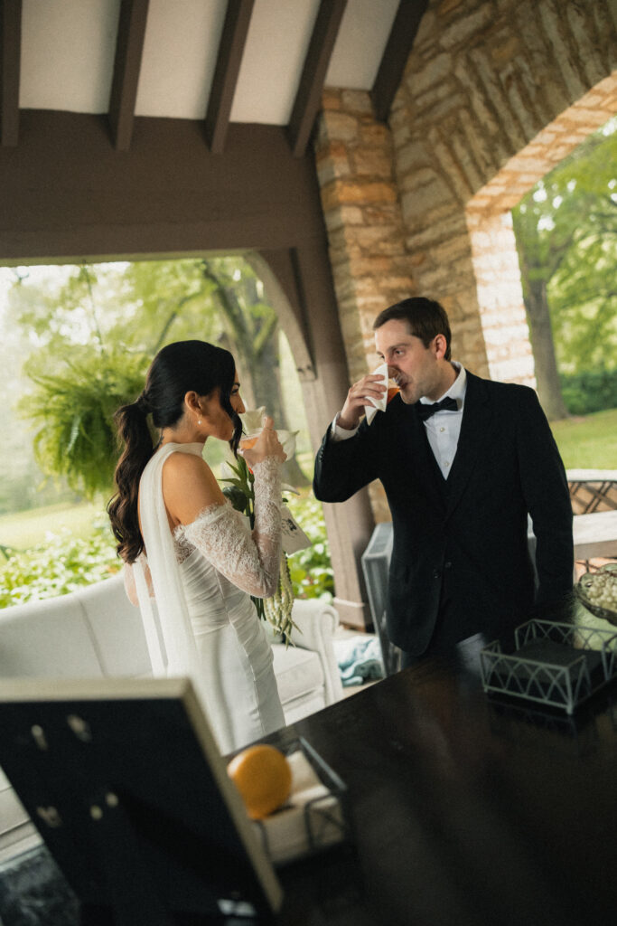 Bride and groom sharing a drink on porch during cocktail hour