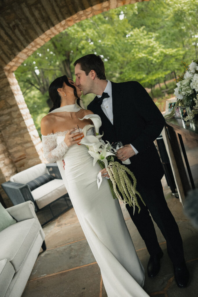 Bride and groom sharing a kiss under stone archway outdoors