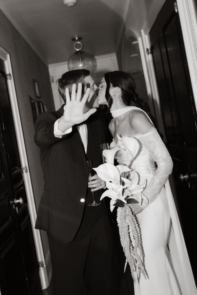 Bride and groom laughing together in black and white, groom covering face