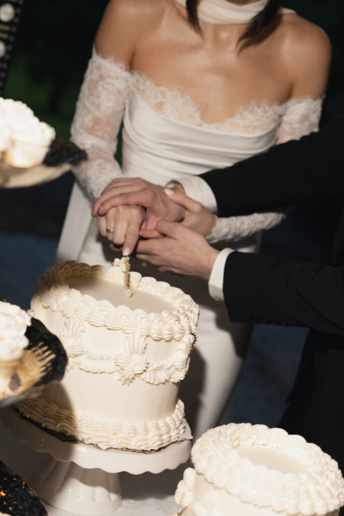Bride and groom cutting wedding cake together, close up hands