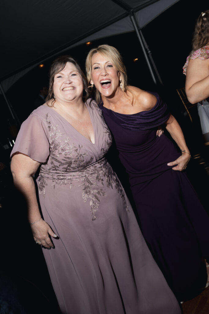 Wedding guests laughing together at reception under tent