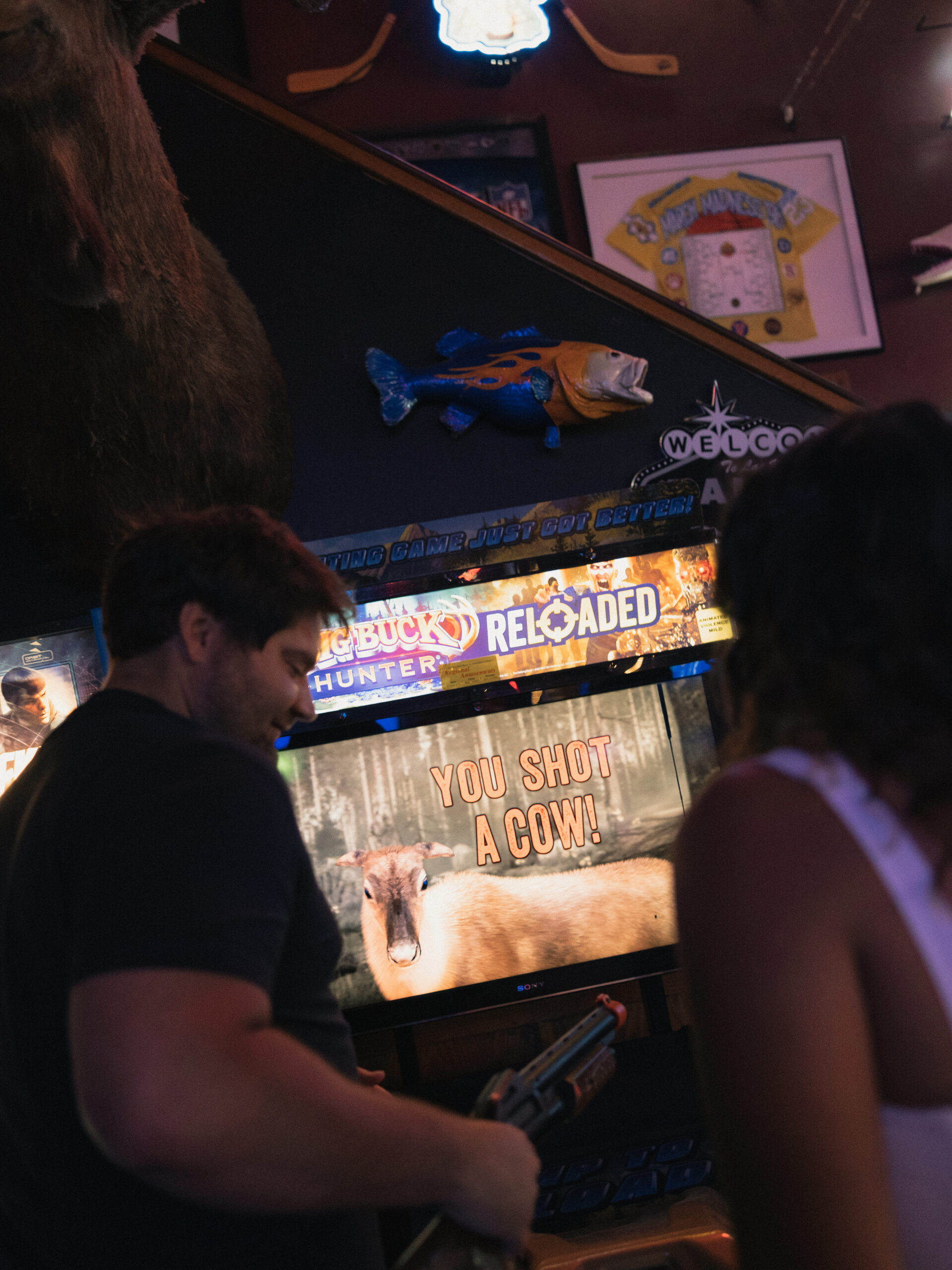 Dave playing arcade game with Samantha standing behind him, colorful screen glow